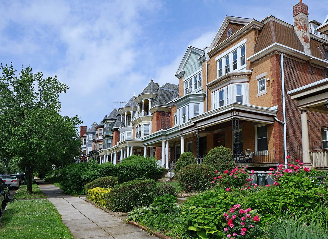 Contact - Suburban Street in Philadelphia with Rows of Older Three Story Brick Homes with Front Porches with Nicely Landscaped Front Yards