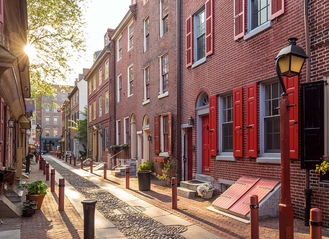 Insurance Solutions - Alley in Philadelphia with Rows of Traditional Red Brick Homes and Antique Lamp Posts at Sunset